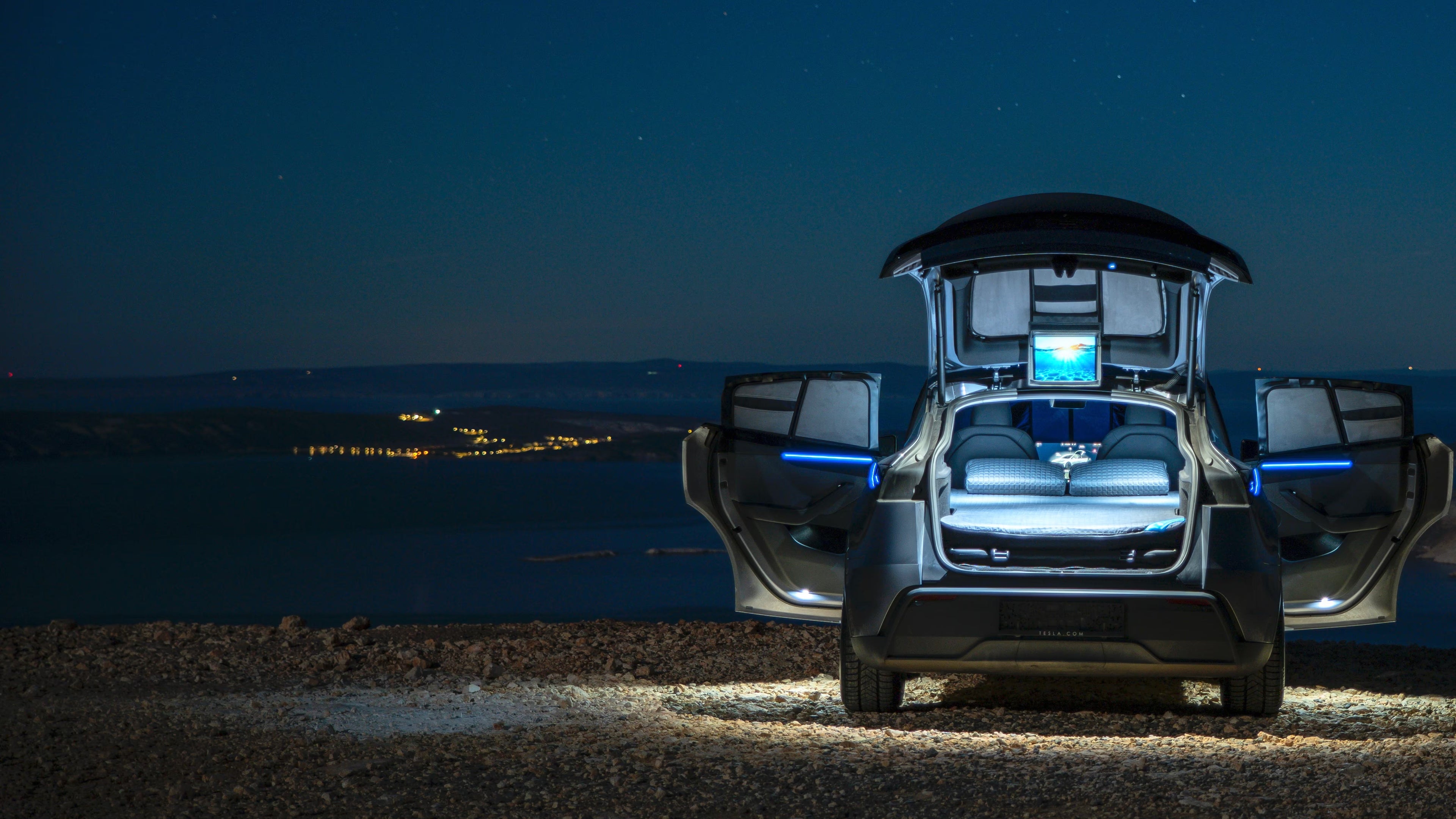 Tesla Model Y night car camping with illuminated interior showing Dreamcase Memory hybrid inflatable bed