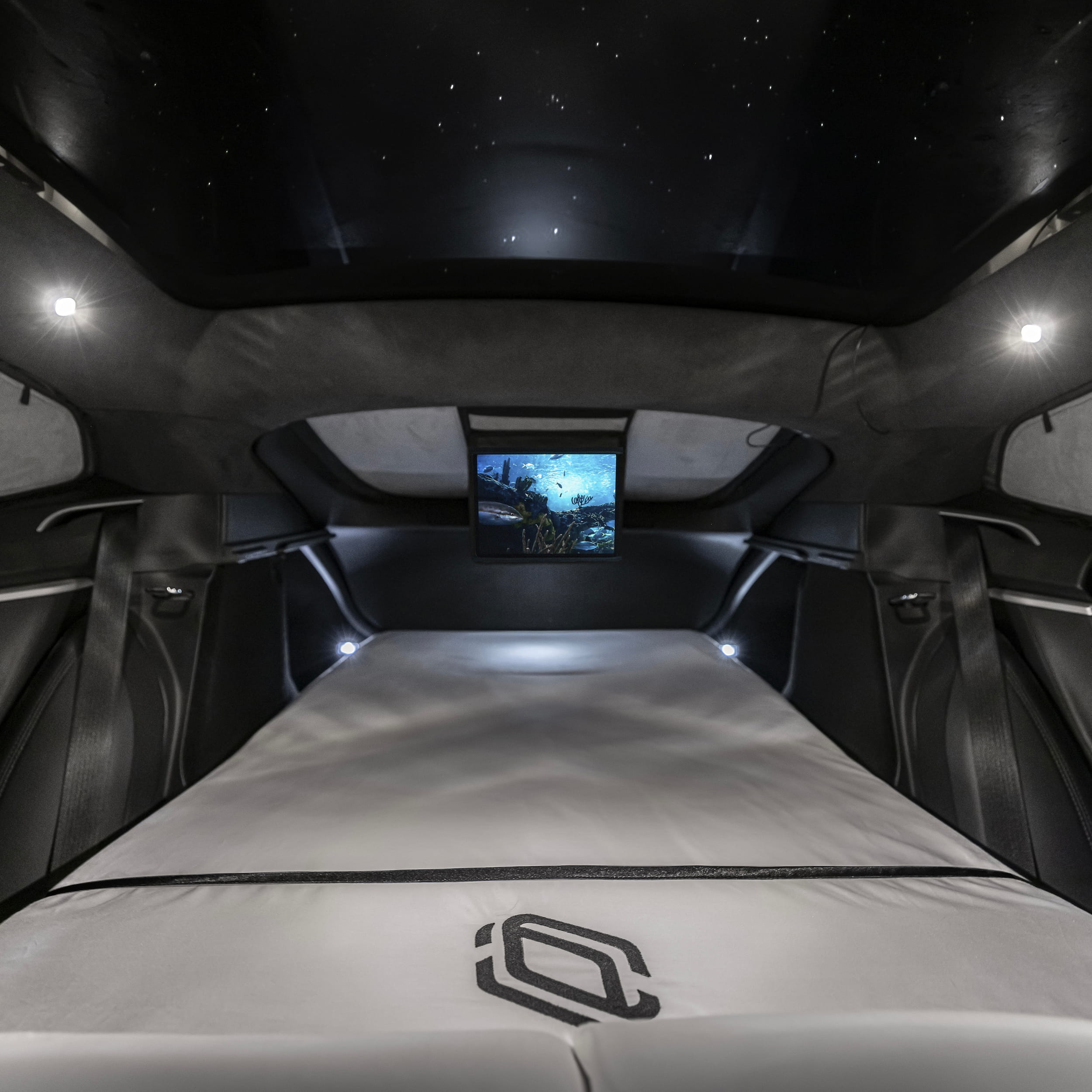 Interior view of the Dreamcase Classic bed setup inside a vehicle with fitted sheet and ambient lighting