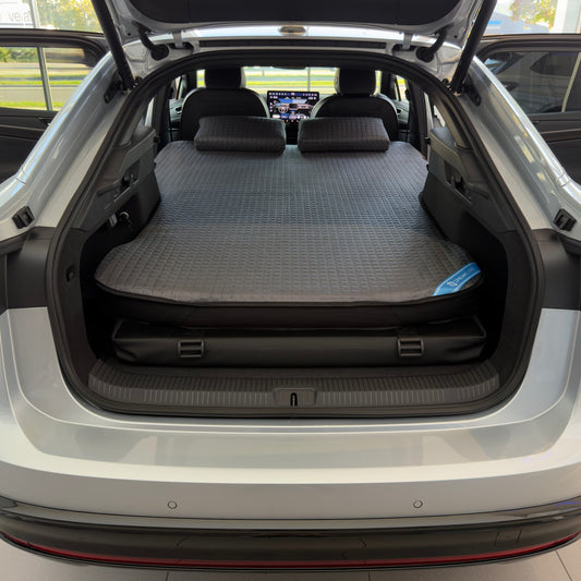 DreamCase Memory car bed fitted in a Volkswagen ID.7, rear hatch open, grey quilted mattress and pillows on the platform
